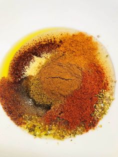 spices are mixed together in a bowl on a white tablecloth with yellow and red colors