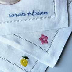 three embroidered napkins on top of each other with fruit and flowers in the middle