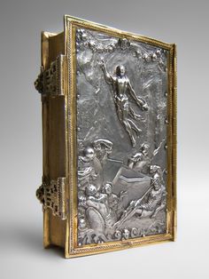 an antique silver and gold book with the image of jesus on it's cover