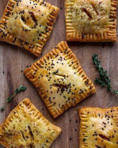 four different types of pastries on a wooden surface with herbs and seasoning sprinkles