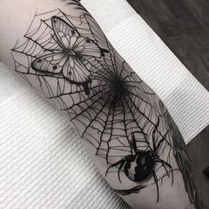 a black and white spider web tattoo on the arm