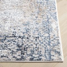 a blue and white area rug on the floor with wood floors in front of it