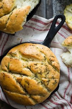 bread in a cast iron skillet on a red and white towel next to some garlic bread