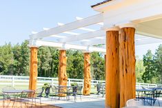 an outdoor dining area with tables and chairs under a pergolated roof, surrounded by trees