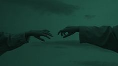 two hands reaching out towards each other in front of a dark green background with clouds