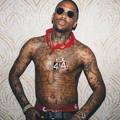 a man with tattoos on his chest wearing sunglasses and a red bandanna around his neck