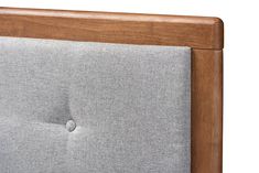 a close up view of the headboard and buttons on a grey fabric bed frame