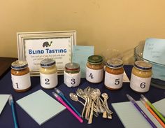 there are many jars and spoons on the table with writing paper next to them