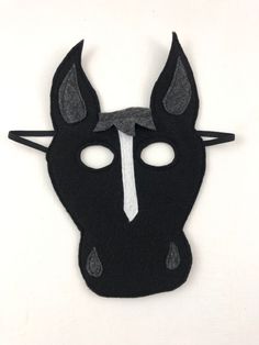 Black felt horse mask with a white stripe down the center of its face. On a white background. Black Novelty Carnival Costume, Fun Black Costume Accessories For Cosplay, Black Novelty Costumes For Costume Party, Black Novelty Costume For Costume Party, Black Costume Accessories For Carnival Gift, Black Carnival Costume Accessories Gift, Black Novelty Costume Accessories For Gift, Handmade Black Costume Accessories, Felt Horse