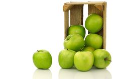 green apples are stacked in a wooden crate