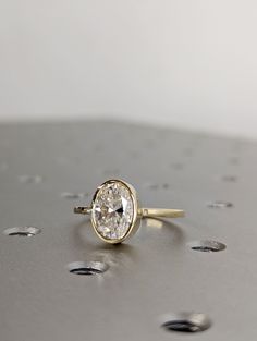 a diamond ring sitting on top of a metal surface with drops of water around it