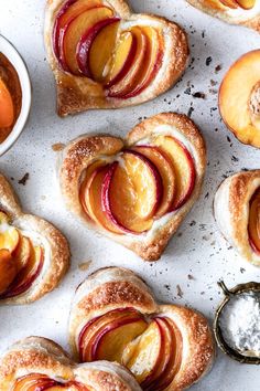 several pastries are arranged on a white surface next to small bowls and spoons