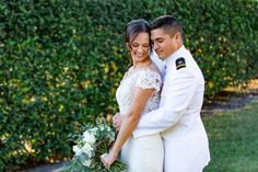 a bride and groom pose for a photo in front of some bushes at their wedding