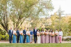 a group of people standing next to each other in front of trees and grass with flowers