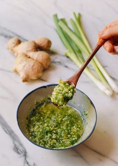 someone is dipping broccoli into a small bowl with some celery on the side