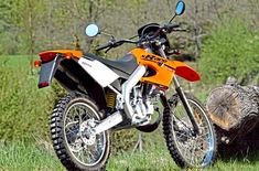 an orange dirt bike parked next to a tree stump