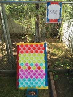 a colorful piece of art sitting on the ground in front of a chain link fence