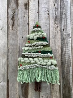 a knitted christmas tree hanging on a wooden fence