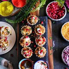 several plates with food on them next to flowers and other bowls filled with different colored powders