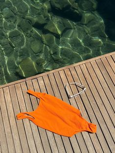 an orange towel laying on top of a wooden floor next to water