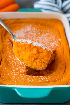 a spoonful of sweet potato dip in a blue dish with carrots behind it