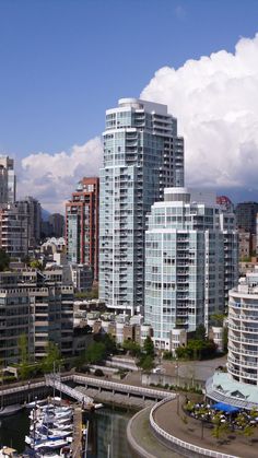 the city is full of tall buildings and boats in the water below them are clouds