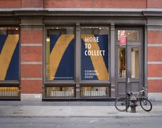 a bike parked in front of a storefront on the side of a street with large windows