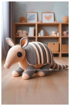 a crocheted stuffed animal sitting on top of a wooden floor next to a book shelf