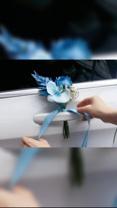 a blue ribbon tied to the back of a white car with flowers on it's side