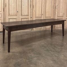 a wooden table sitting on top of a cement floor next to wood paneled doors