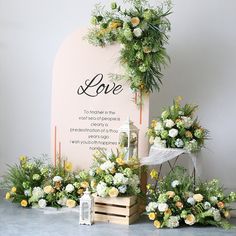 flowers and greenery are arranged in front of a love sign