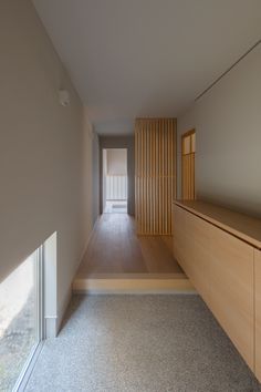 an empty hallway leading to another room with wood paneling on the walls and floor