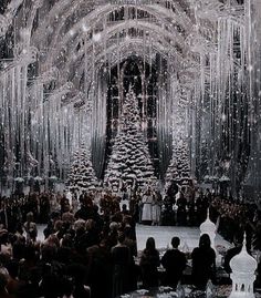 a large group of people standing in front of a christmas tree with lights on it