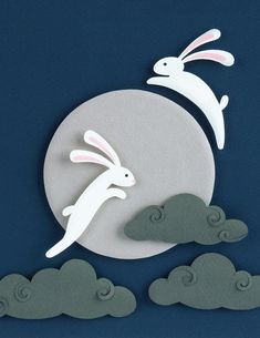 two paper rabbits are flying over the clouds