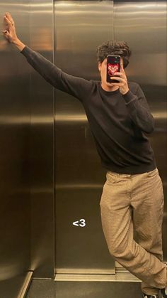 a man taking a selfie while standing in front of an elevator with his cell phone