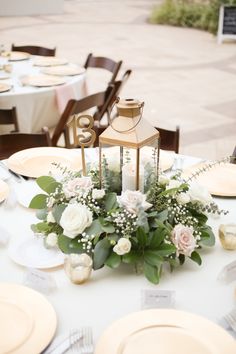 a table set with plates, silverware and a lantern centerpiece on top of it