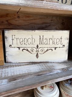 a french market sign sitting on top of a wooden shelf next to jars and containers