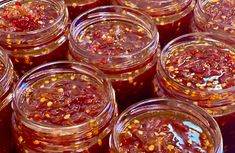 many jars filled with different kinds of jams on top of each other in rows