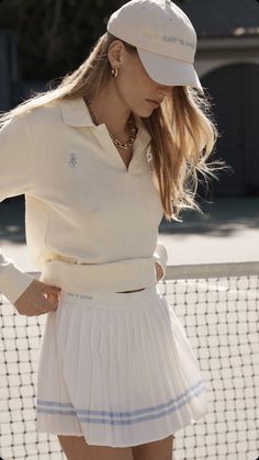 a woman wearing a white tennis outfit and hat