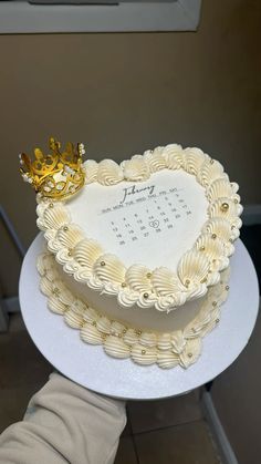 a heart shaped cake with a golden crown on top is being held by someone's hand