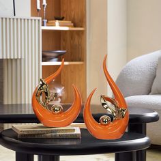 two orange sculptures sitting on top of a black table in front of a white couch