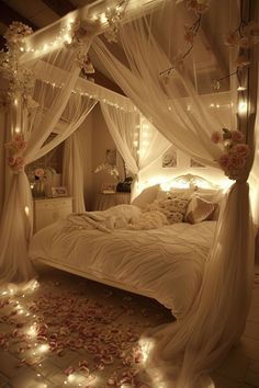 a bed with white curtains and lights on the headboard is lit up by fairy lights