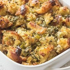 a casserole dish with bread and vegetables in it on a white table cloth