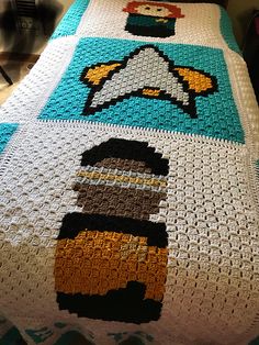 a crocheted blanket with an image of a cartoon character on it, sitting on top of a bed