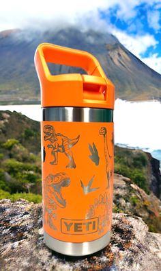 an orange yeti water bottle sitting on top of a rock