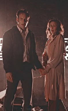 two people standing next to each other holding hands