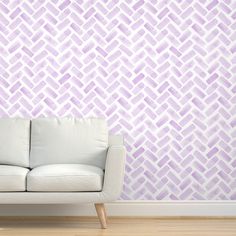 a white couch sitting in front of a wall with a purple pattern on the wall