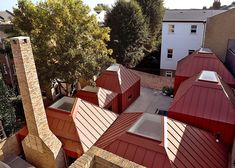 an aerial view of several red roofs in a residential area with trees and buildings behind them