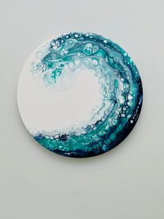 a white plate with blue and green swirls on it's side, sitting on a table