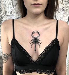 a woman wearing a bra with a scorpion tattoo on her chest and under the bra